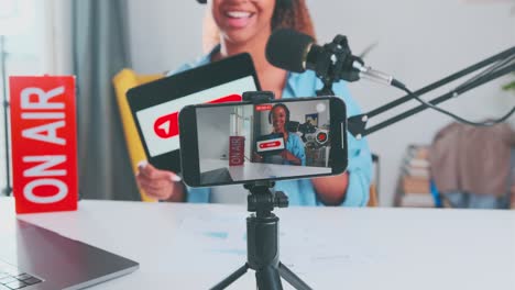 joven mujer afroamericana anfitriona de blog sostiene una tableta electrónica con signo de compartir