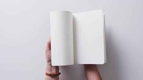 close up de la mano hojeando un libro con espacio de copia en un fondo blanco en cámara lenta