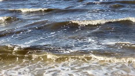 The-waves-along-the-seashore-slowly-rolling-in-over-the-sand-in-slow-motion