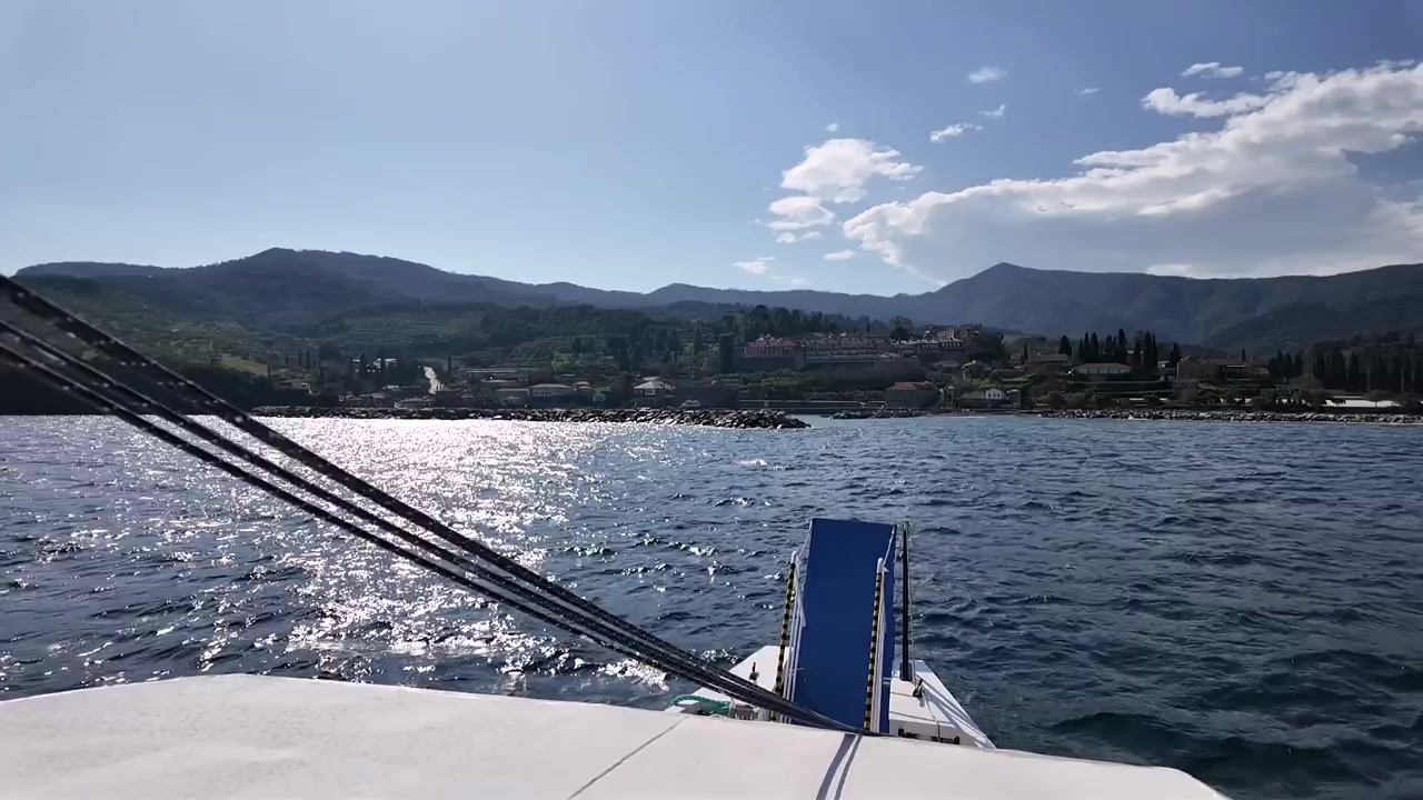 Una barca si muove sull'acqua mentre il sole splende. Le colline e gli edifici lungo la riva sono visibili. Relax e divertimento sono il fulcro di questo viaggio.