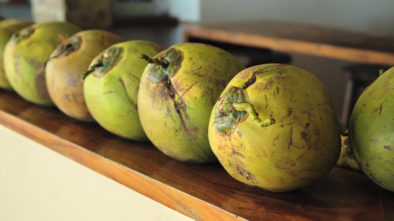 Primo piano di noci di cocco buko fresche disposte su un tavolo di legno in un ambiente tropicale