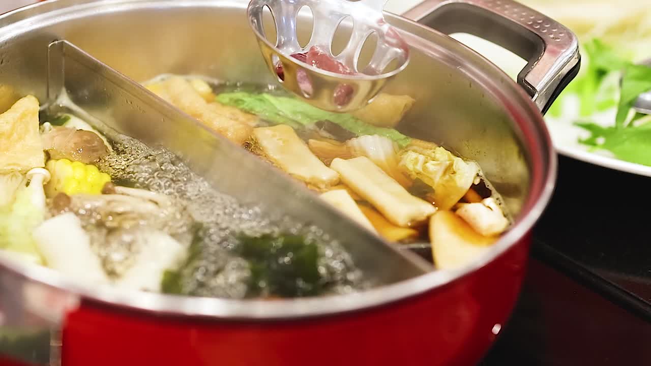 A close-up view of a hotpot filled with vegetables and broth, showcasing the cooking process.