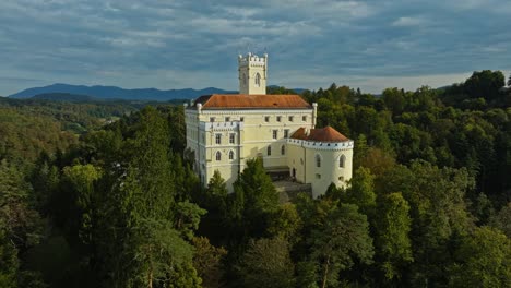 trakoscan castle surrounded by forested hills in croatia - aerial shot