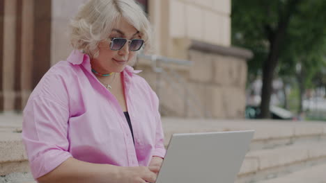 mujer trabajando en una computadora portátil al aire libre en las escaleras