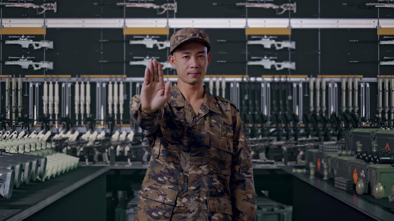Asiatisk mandlig soldat ser på kameraet og udtrykker sin utilfredshed uden håndtegn i militært våbenlager