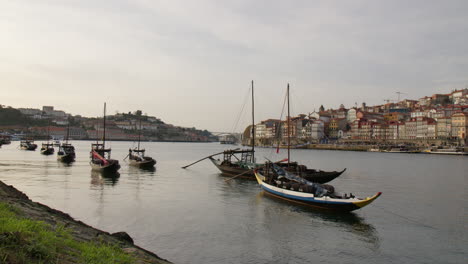 traditional rabelo boats with wine barrels in douro river in porto, portugal. wide static shot