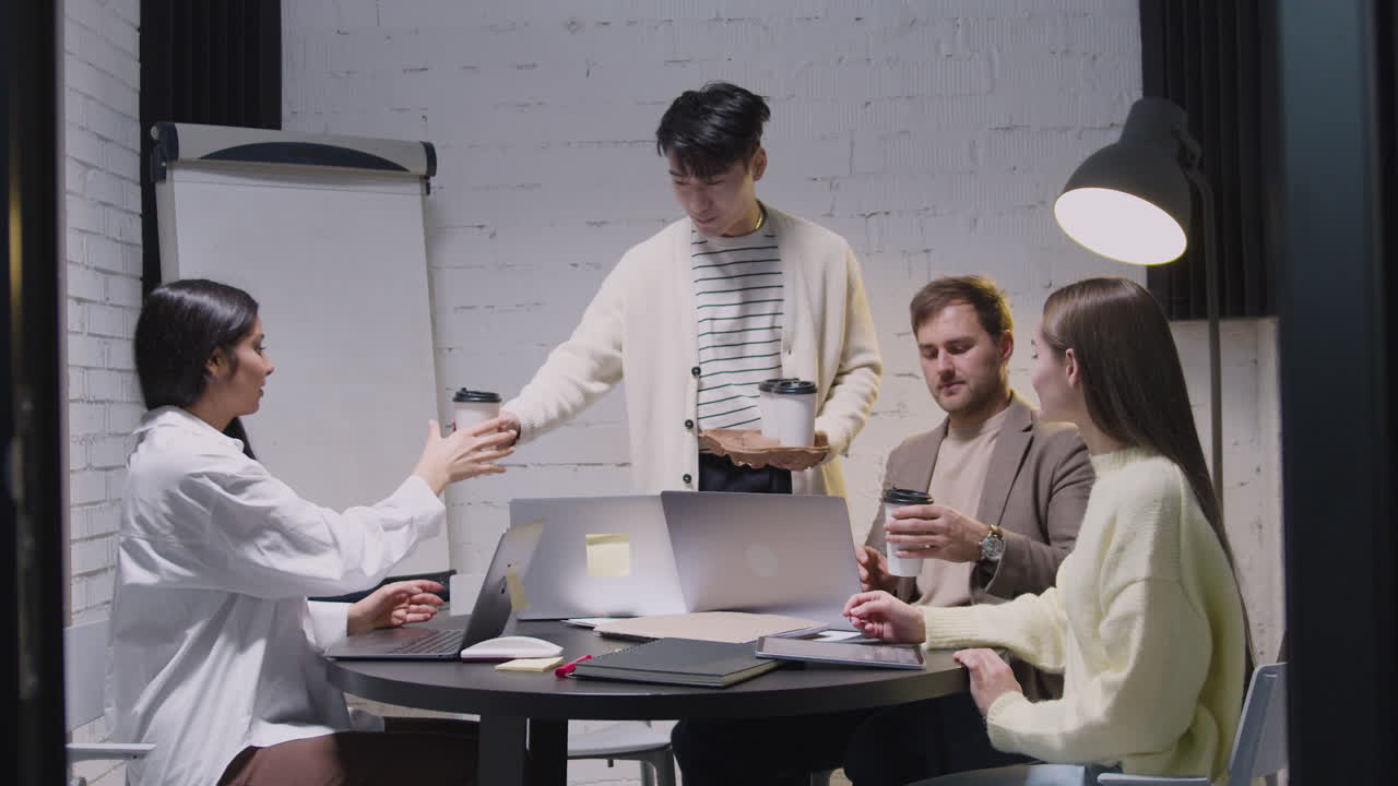 팀 회의 중에 행복한 동료들에게 테이크아웃 커피를 가져오는 청년