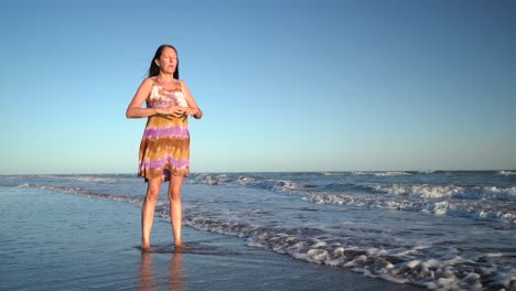 a woman performing a breathing exercise at the seaside. full body shot