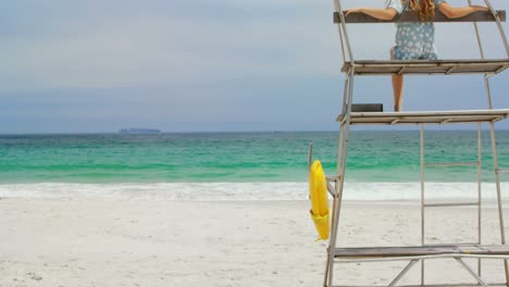 Vista-Trasera-De-Una-Mujer-Sentada-En-La-Torre-De-Observación-En-La-Playa-4k