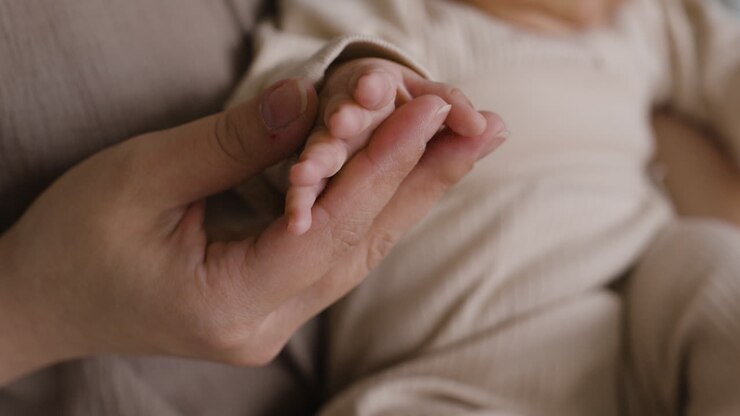 Baby houdt moeders hand vast
