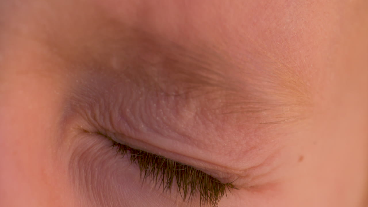 macro en cámara lenta cerca de un niño pequeño cerrando firmemente su ojo azul