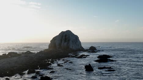 dolly aéreo en el islote de peña blanca y las olas que golpean la costa rocosa al amanecer o al atardecer en chile, américa del sur