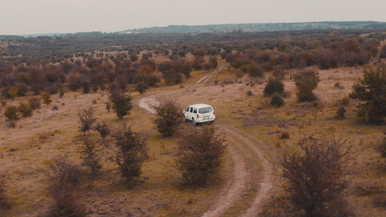 jeep blanco conduciendo por un camino rural de tierra en una estepa marrón de otoño