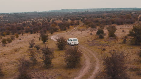 jeep blanco conduciendo por un camino rural de tierra en una estepa marrón de otoño