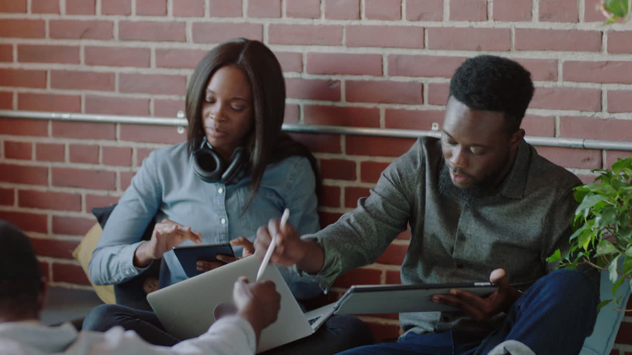 young african american business team using mobile computer technology brainstorming sharing development ideas students relaxing studying in startup company office