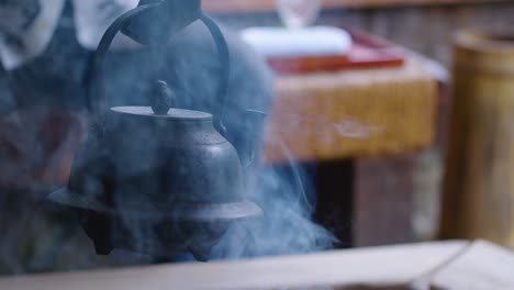 전통적인 일본 주전자는 뜨거운 물을 끓이기 위해 연기가 자욱한 화덕 위에 매달려 있습니다.