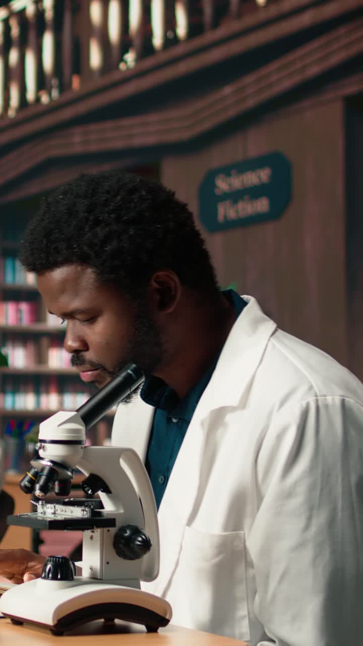 Scienziato afroamericano guarda al microscopio e sorride