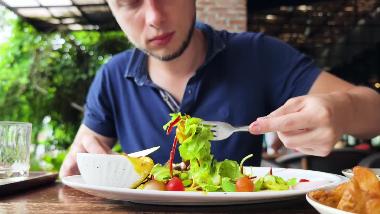 hombre comiendo ensalada en un restaurante