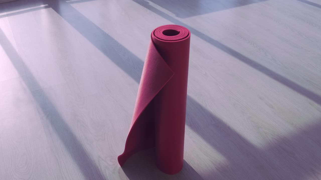 A vibrant red yoga mat stands upright on a wooden floor, capturing the play of sunlight and shadows in a serene indoor environment, perfect for workouts or relaxation