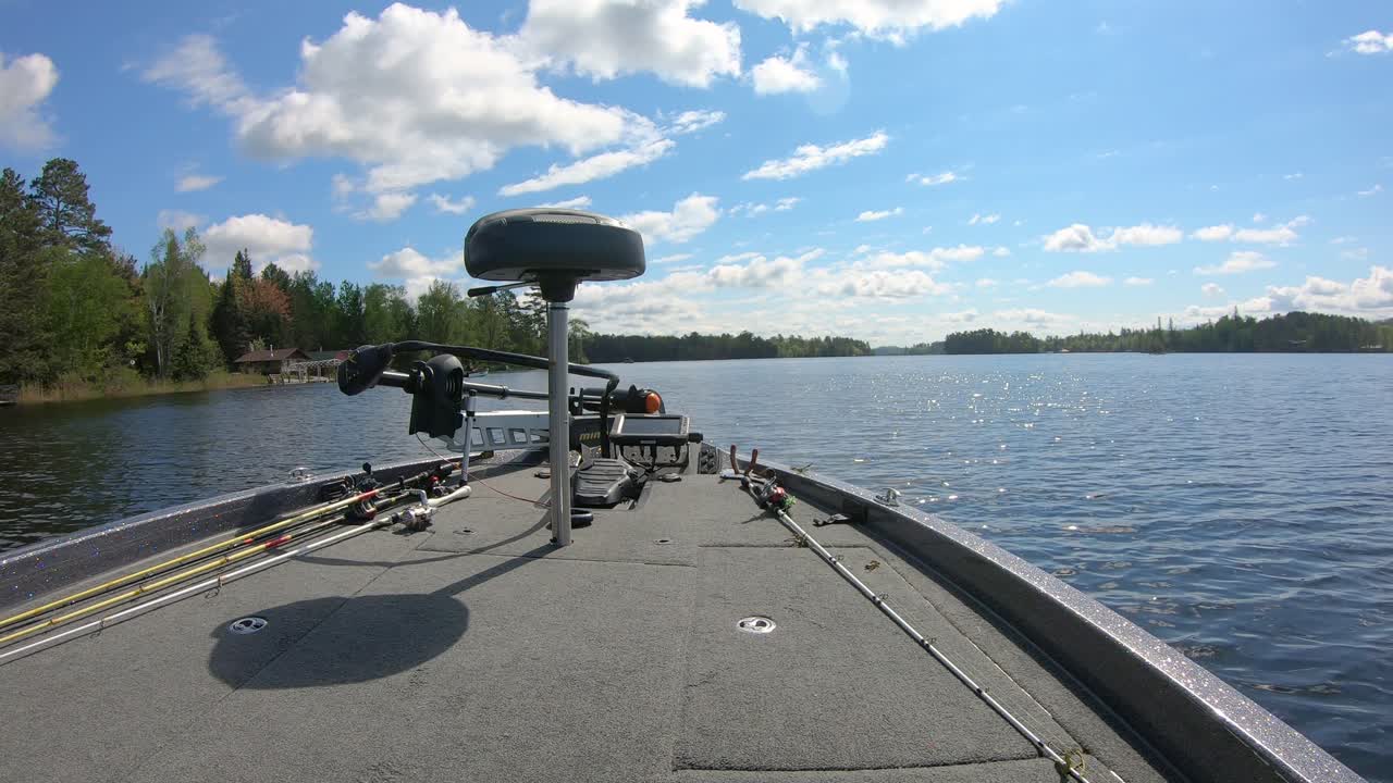 Front deck of bass fishing boat while slowly cruising by lake homes on Lake Vermilion on summer day in northern Minnesota