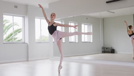 caucasian female ballet dancer practicing ballet during a dance class in a bright studio