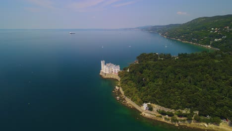 The-beautiful-Miramare-Castle,-standing-proudly-in-front-of-the-sea,-can-be-viewed-through-a-drone-camera