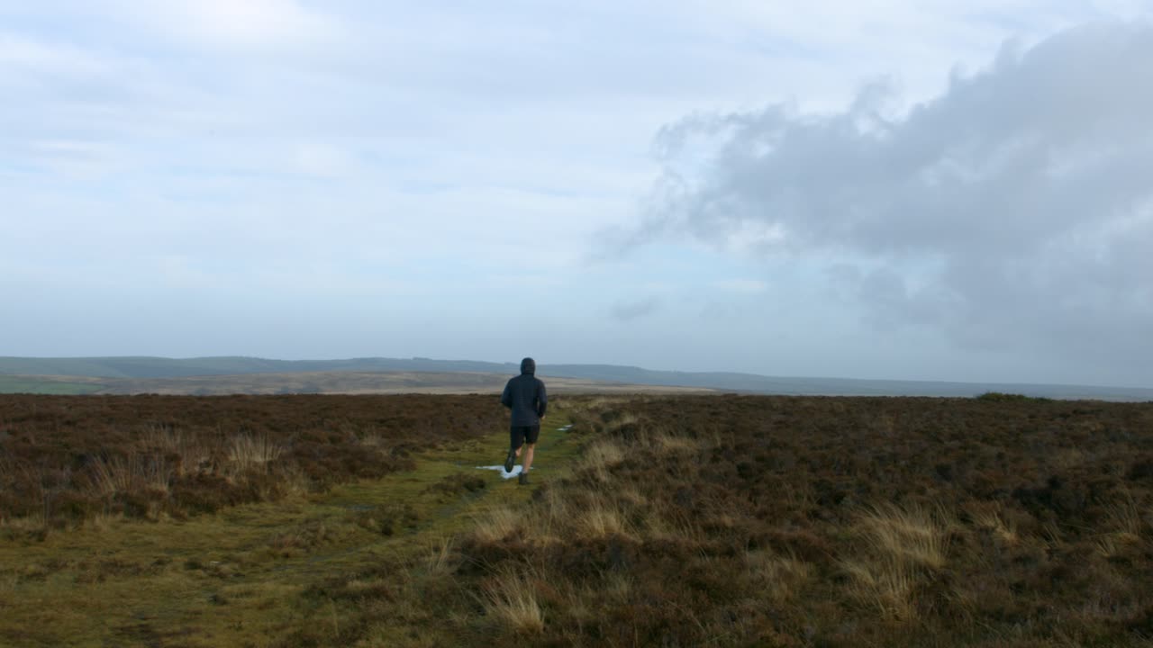 atleta masculino pasando por el entrenamiento de la cámara para el maratón sobre el campo rural en exmoor manteniendo un estilo de vida saludable uk 4k