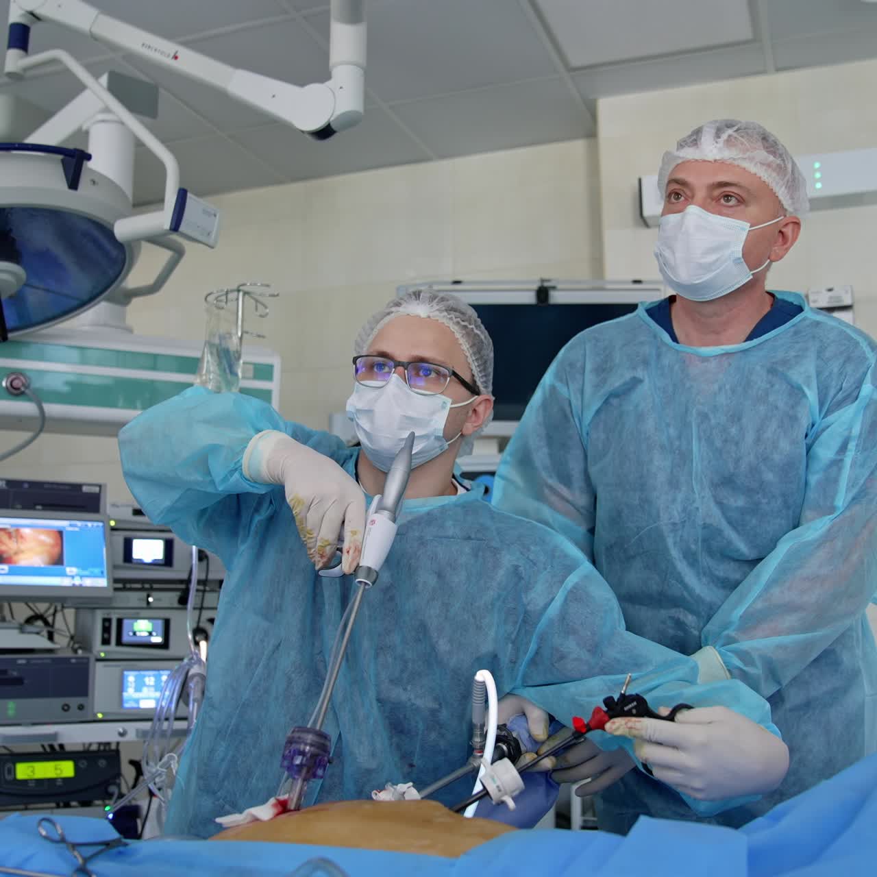 Dos médicos mirando el monitor en la unidad de cuidados intensivos. Grupo de cirujanos en el quirófano con equipo quirúrgico