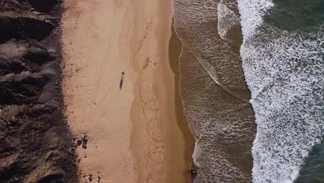 a view from above of a couple walking along the beach in algarve, portugal