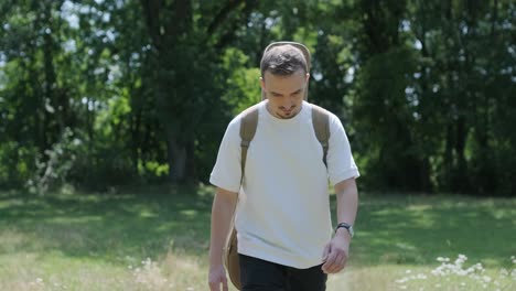 young man walking with guitar on street near forest