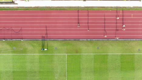 People-during-Early-morning-Jogging-on-a-racetrack-with-long-starched-silhouettes,-Aerial-view