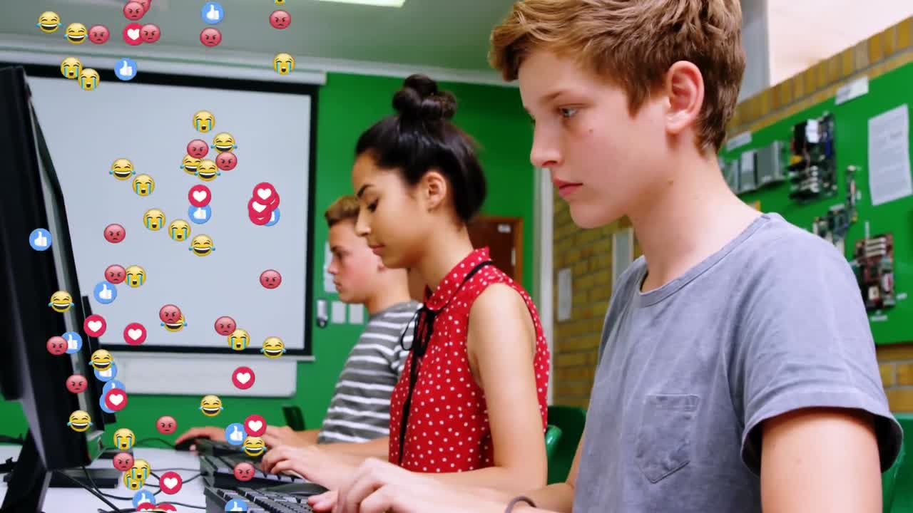Animation of emoticons over happy diverse students using computers at school