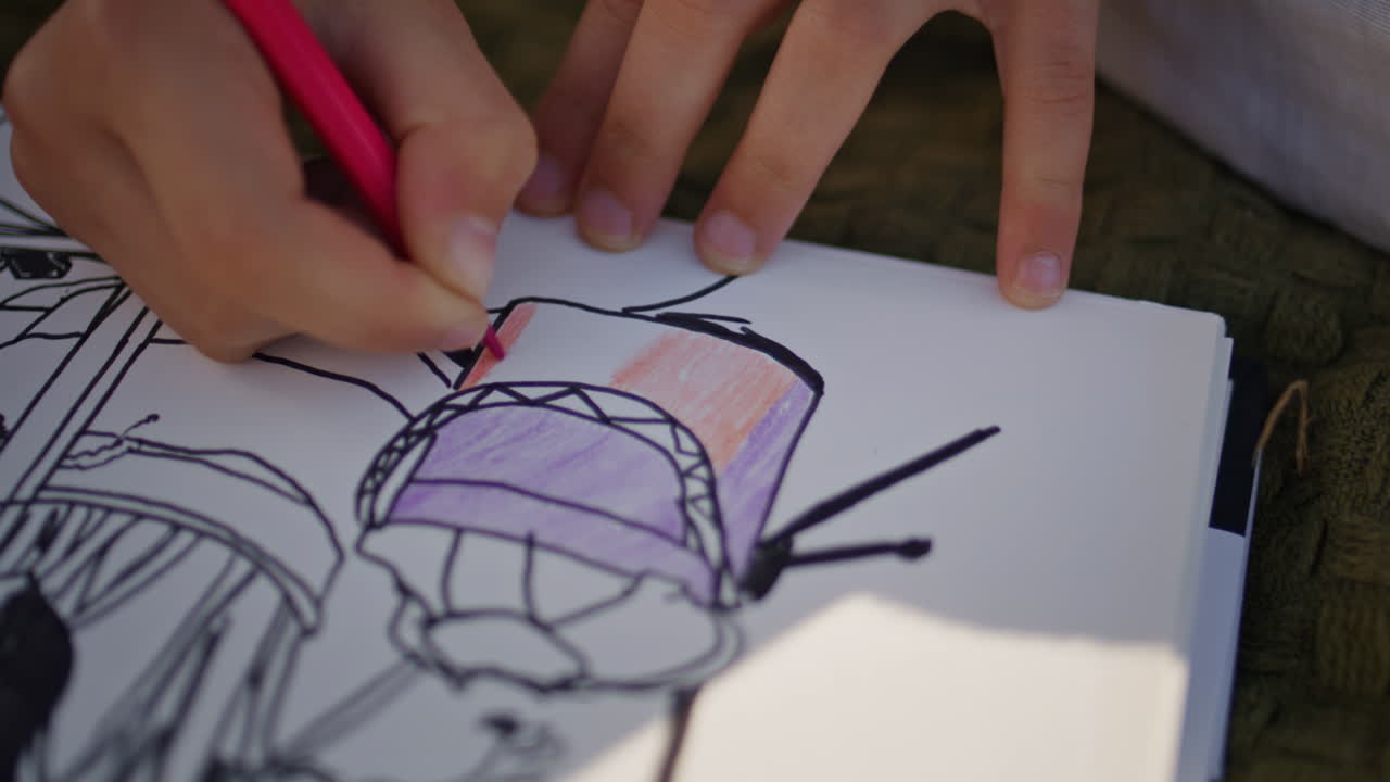 Small child hands drawing album at summer picnic closeup. Unknown kid creating