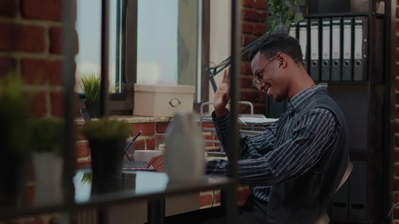 Business man waving at video call webcam in startup office