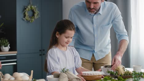 Kleines-Mädchen-Hilft-Eltern-Beim-Vorbereiten-Des-Ostertisches-Für-Das-Abendessen.