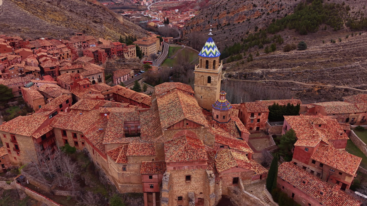Historic Albarracin old town in Aragon, Spain, with terracotta rooftops, medieval stone buildings and a cathedral with ornate tiled blue domes nestled in a rocky valley
