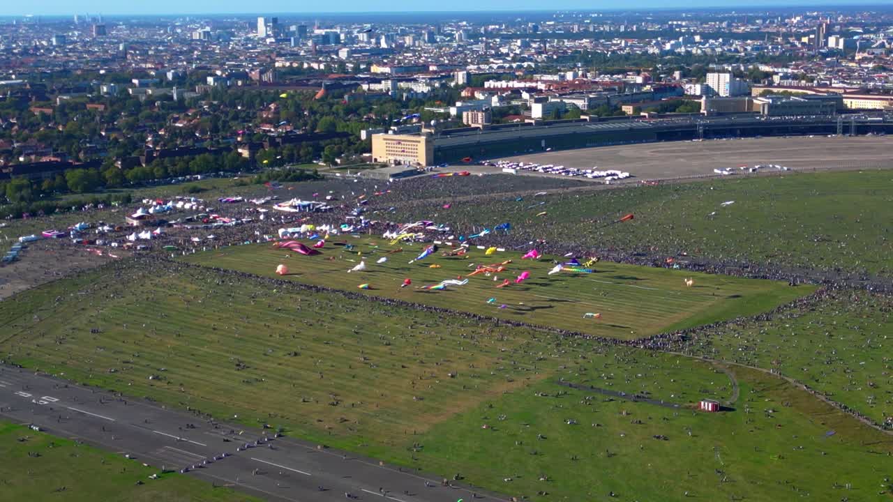 Large crowd of people gathering at the Tempelhofer Feld giant kite festival in Berlin, Germany. Lovely aerial view flight ascending drone