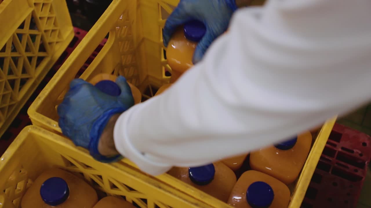 Operaio di fabbrica che imballa succo fresco imbottigliato in casse container gialle per la spedizione