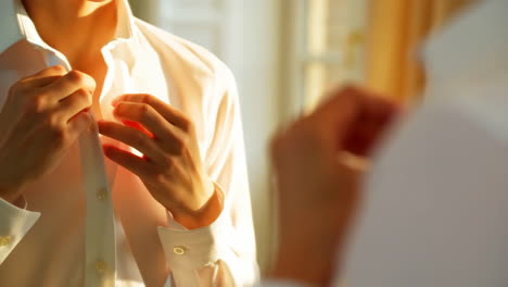 man buttoning a white shirt