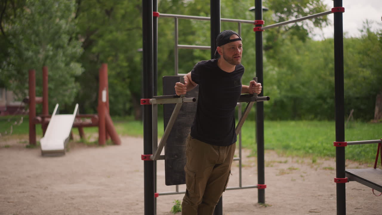 Caucasian Man Performing Seated Dip Exercise. Seated Dip Movement Targets Chest And Triceps, Controlled Descent And Push, Instructional Vibe, Rugged Equipment Surrounded By Trees