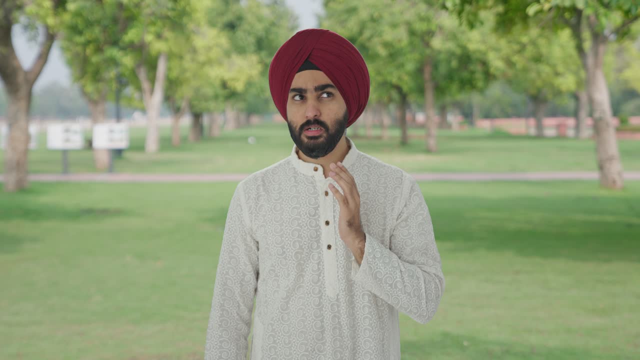 Uomo indiano sikh malato che soffre di mal di denti nel parco