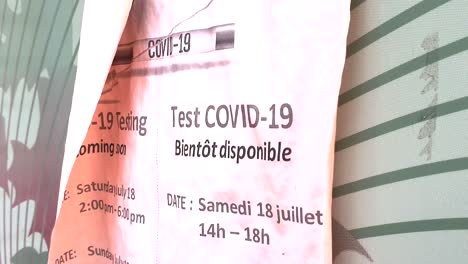 pink poster for covid-19 covid coronavirus test site written in english and french posted on end of community mailbox