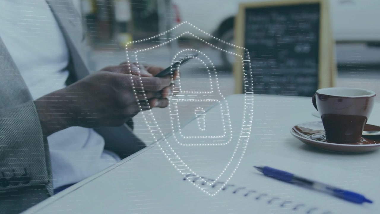 Man using phone at cafe, causing security shield overlay fading and pulsing over notebook and phone