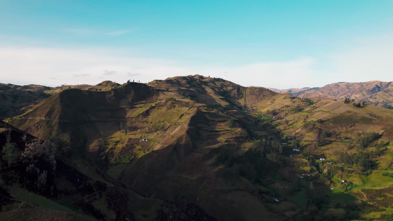 L'immensa e aspra catena montuosa vicino a Quilotoa, Ecuador. I ripidi pendii presentano un contrasto tra terra arida e fogliame verde sotto un cielo azzurro.
