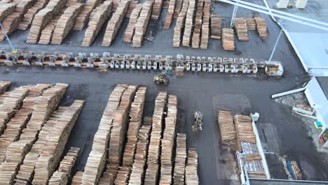 overhead perspective of wood manufacturing facility in germany, with stacks of pine logs and busy machinery at work