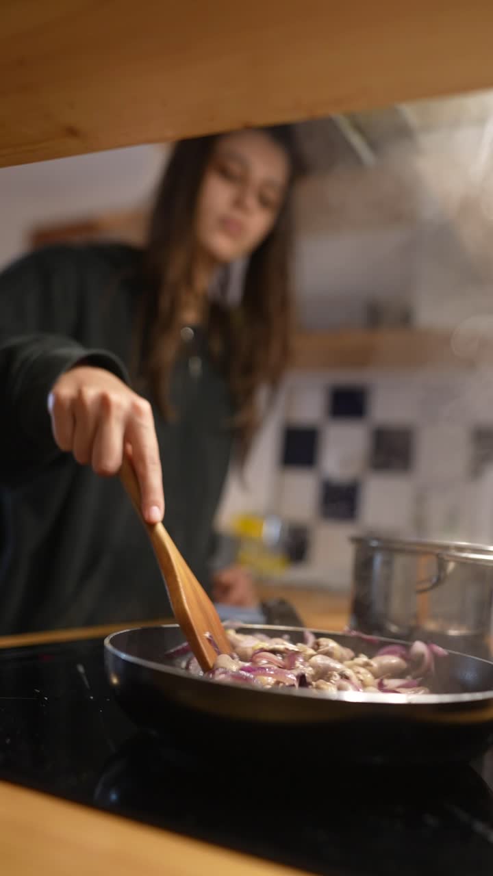 una mujer joven cocinando cebollas.