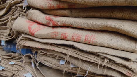 stacks of used natural hessian jute coffee sacks in a coffee production warehouse to store coffee beans for distribution