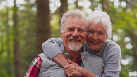 portrait of loving retired senior couple walking in woodland countryside together