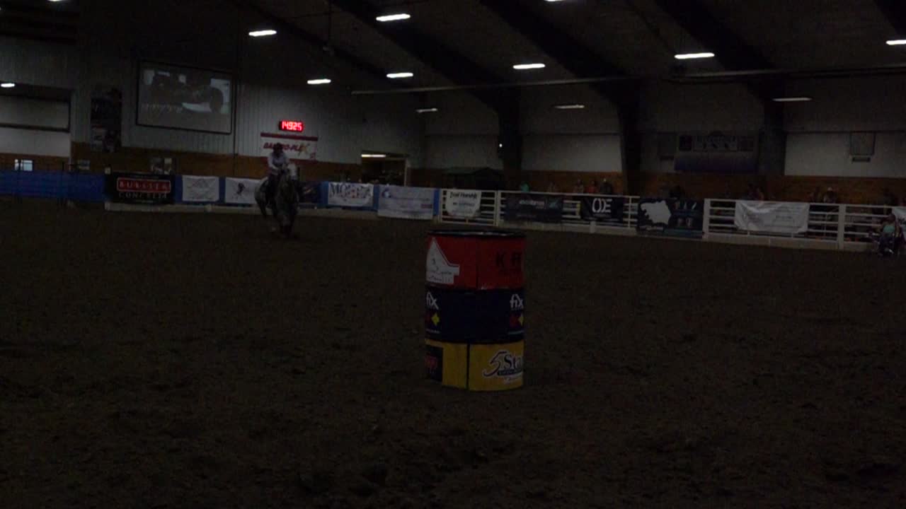 Donna che fa Barrel Racing a Cavallo in un'Arena Equestre Interna
