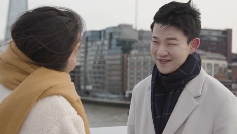 young asian couple with romantic man proposing to woman against city skyline 1